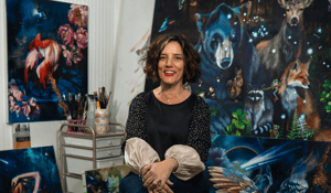 Elli sitting in front of animal paintings 